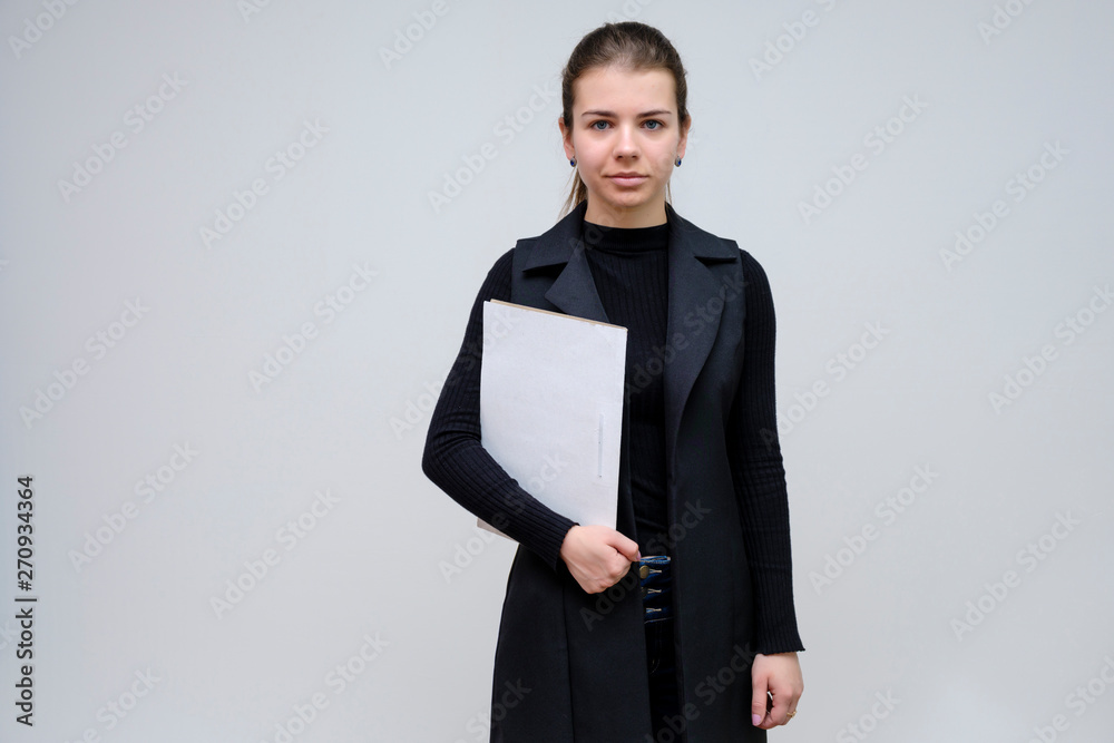 Photo portrait of a beautiful smiling brunette business woman with a folder on a white background in a black business suit with long beautiful dark hair in the studio. Photo portrait of a beautiful smiling brunette business woman with a folder on a white background in a black business suit with long beautiful dark hair in the studio.