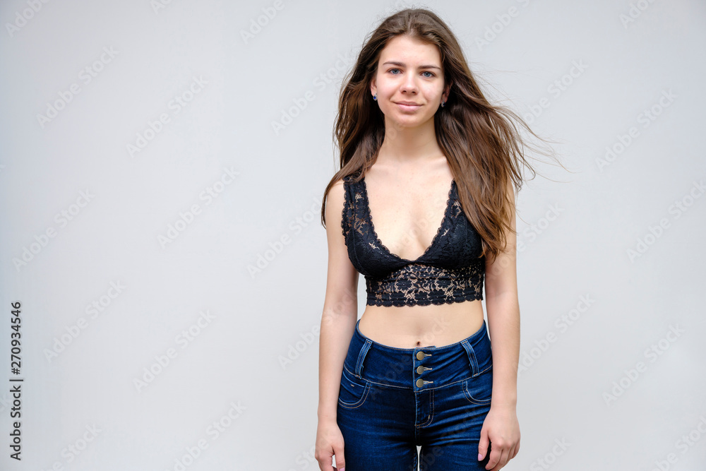 Photo portrait of a beautiful smiling brunette woman girl on a white background in jeans and a blouse with long beautiful flowing dark hair in the studio. Photo portrait of a beautiful smiling brunette woman girl on a white background in jeans and a blouse with long beautiful flowing dark hair in the studio.