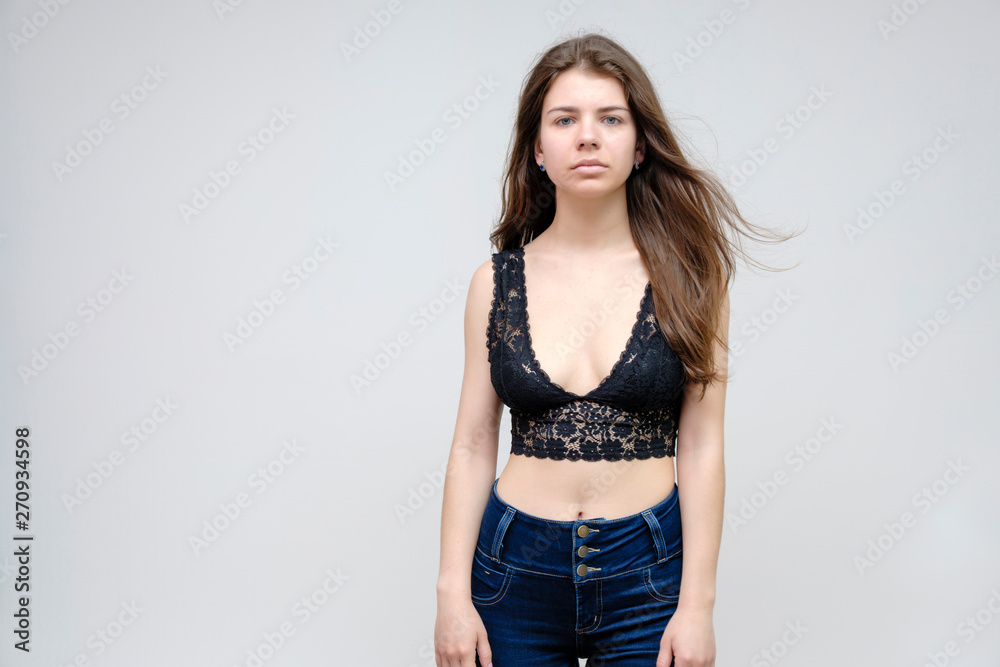 Photo portrait of a beautiful smiling brunette woman girl on a white background in jeans and a blouse with long beautiful flowing dark hair in the studio. Photo portrait of a beautiful smiling brunette woman girl on a white background in jeans and a blouse with long beautiful flowing dark hair in the studio.