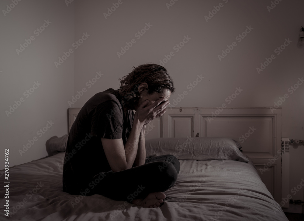 Fototapeta premium Desperate lonely teenager man suffering from depression sitting alone on bed