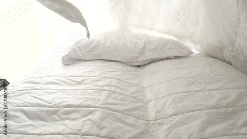 Hands bedding white blanket with natural light from window, slow motion