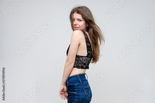 Photo portrait of a beautiful smiling brunette woman girl on a white background in jeans and a blouse with long beautiful flowing dark hair in the studio.