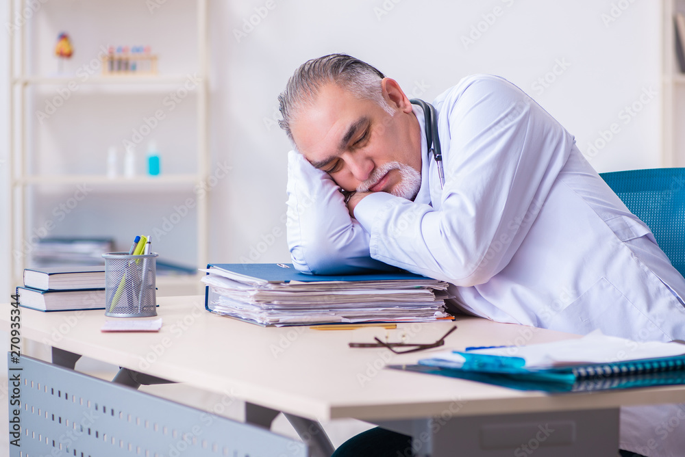 Old male doctor working in the clinic Old male doctor working in the clinic