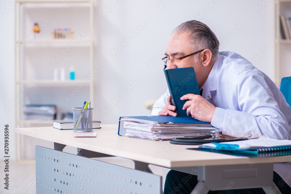Old male doctor working in the clinic Old male doctor working in the clinic