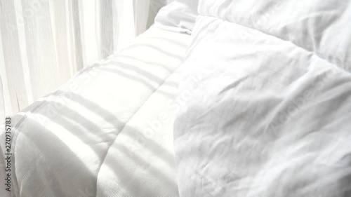 Opening white blanket from bed, slow motion.