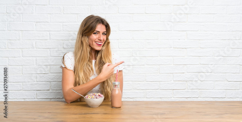 Young blonde woman with bowl of cereals pointing to the lateral