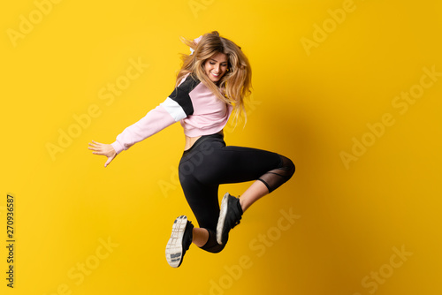 Fototapeta Naklejka Na Ścianę i Meble -  Urban Ballerina dancing over isolated yellow background and jumping