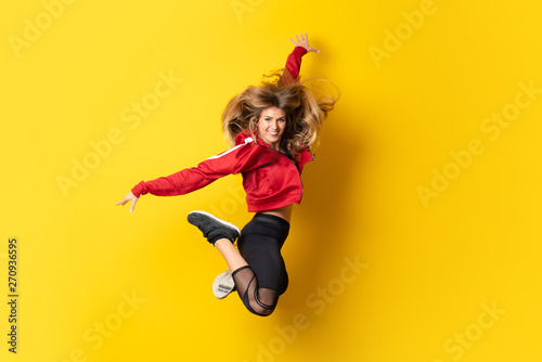 Fototapeta Naklejka Na Ścianę i Meble -  Urban Ballerina dancing over isolated yellow background and jumping