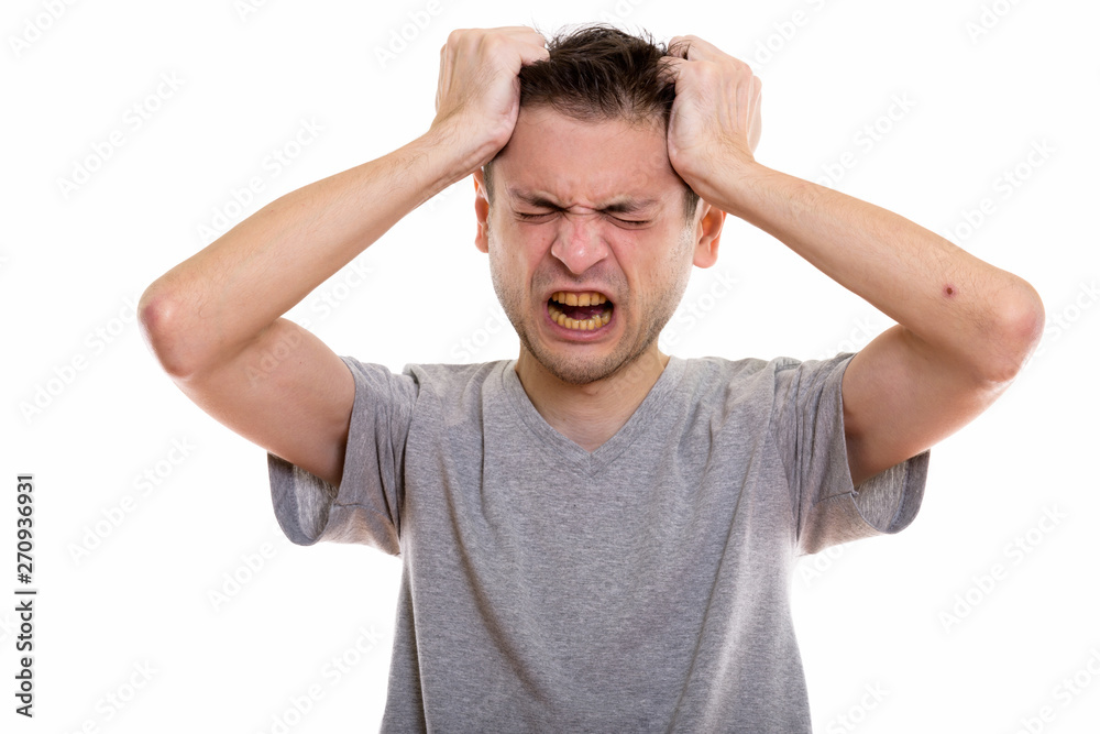 Studio shot of angry young man pulling his hair Studio shot of angry young man pulling his hair