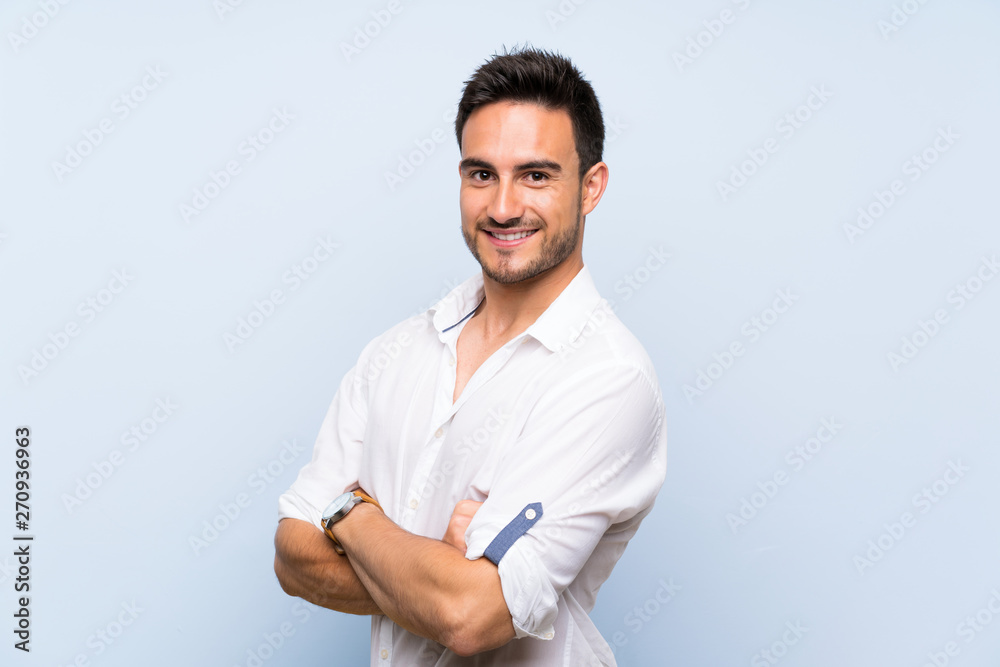 Handsome young man over isolated blue background with arms crossed and looking forward Handsome young man over isolated blue background with arms crossed and looking forward