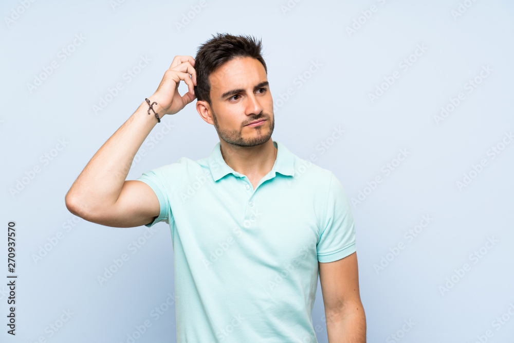Handsome young man over isolated background having doubts while scratching head Handsome young man over isolated background having doubts while scratching head