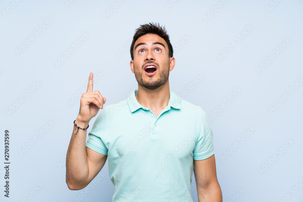 Handsome young man over isolated background pointing up and surprised Handsome young man over isolated background pointing up and surprised