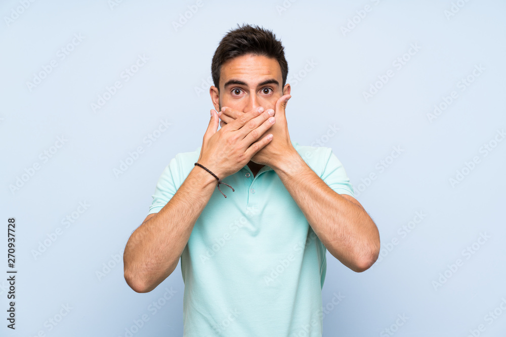 Handsome young man over isolated background covering mouth with hands Handsome young man over isolated background covering mouth with hands