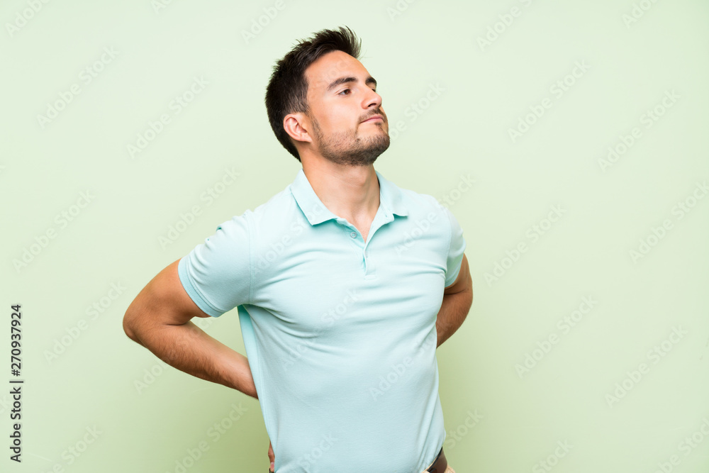 Handsome young man over isolated background suffering from backache for having made an effort Handsome young man over isolated background suffering from backache for having made an effort