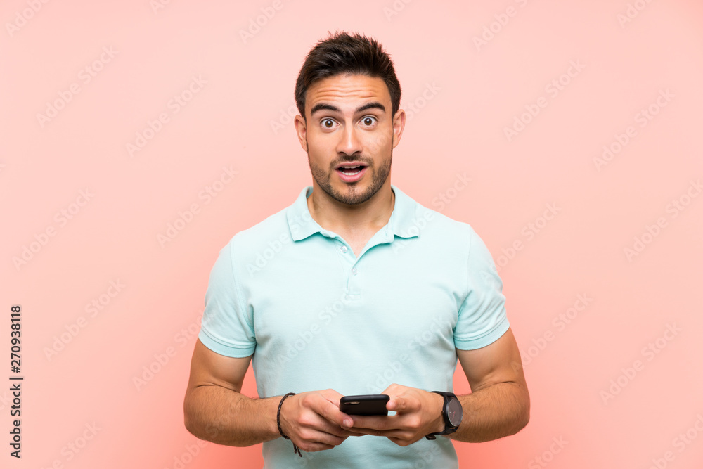 Handsome young man over isolated background surprised and sending a message Handsome young man over isolated background surprised and sending a message
