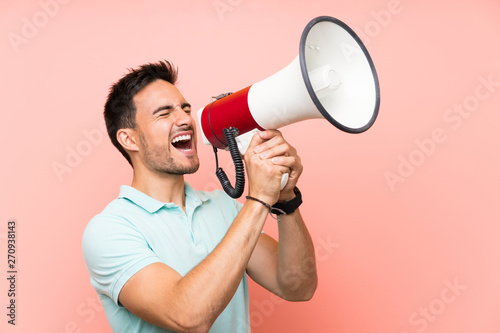 Handsome young man over isolated background shouting through a megaphone