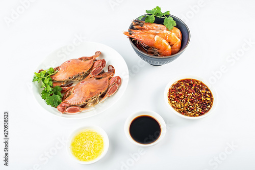 A dish of steamed three-pointed crab and a bowl of boiled shrimp on a white background