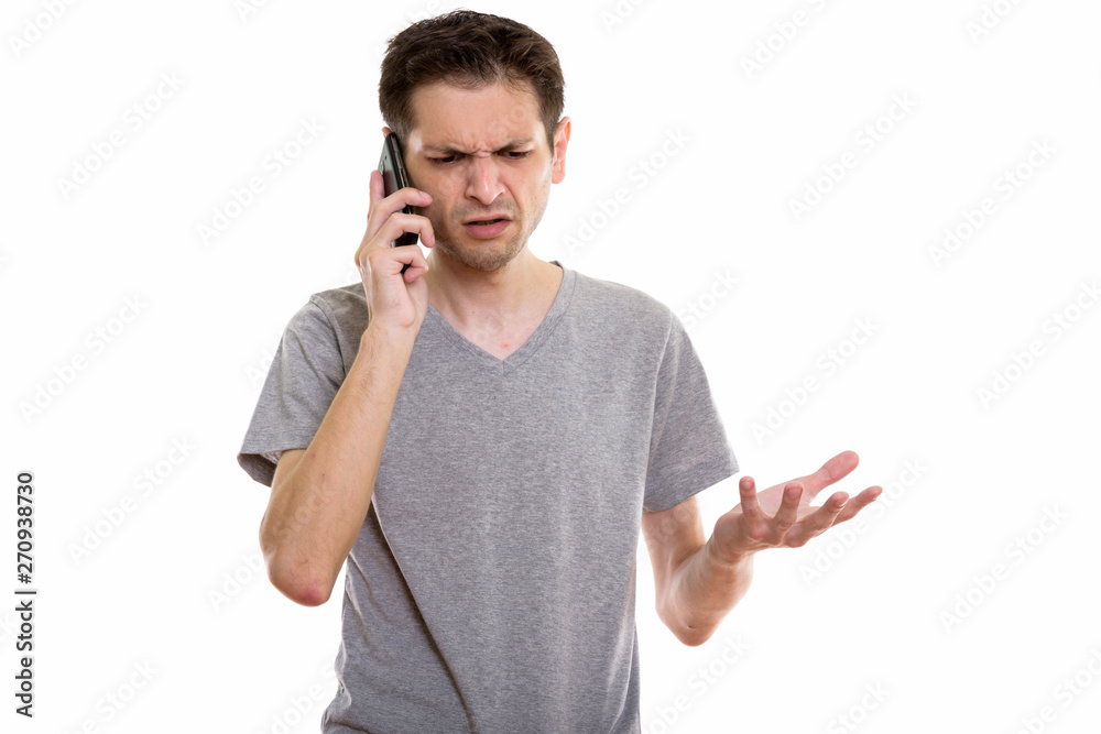 Studio shot of angry young man talking on mobile phone