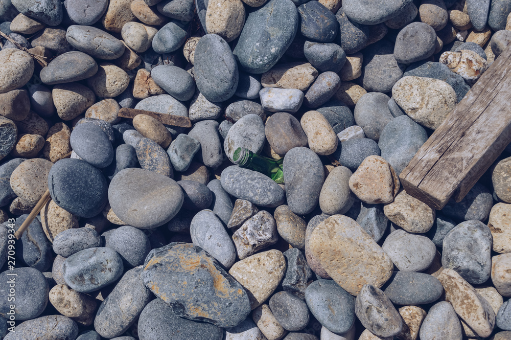 broken glass bottle inside of pebbles on the beach broken glass bottle inside of pebbles on the beach