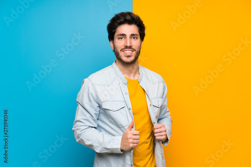 Handsome over isolated colorful background keeping the arms crossed in frontal position