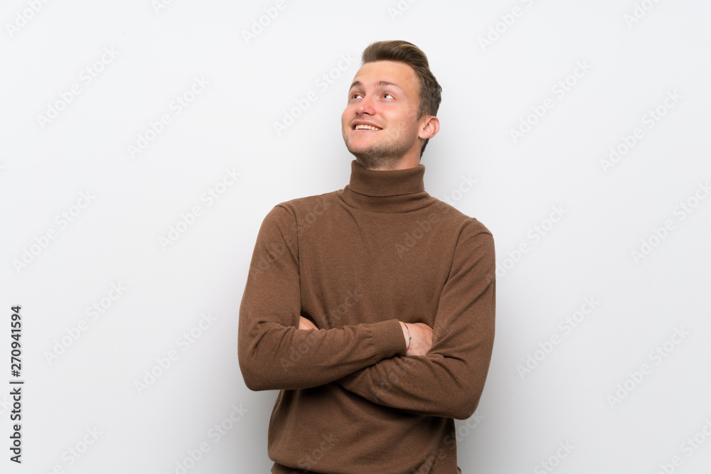 Blonde man over isolated white wall looking up while smiling Blonde man over isolated white wall looking up while smiling