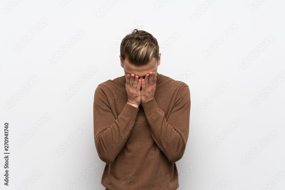 Blonde man over isolated white wall with tired and sick expression Blonde man over isolated white wall with tired and sick expression