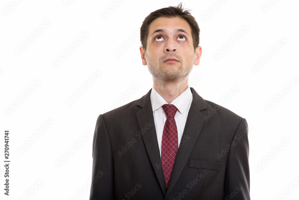 Studio shot of young businessman thinking while looking up Studio shot of young businessman thinking while looking up
