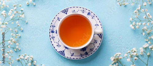 Panel kuchenny z motywem Cup of tea with fresh flowers on blue background. Top view. Copy space.