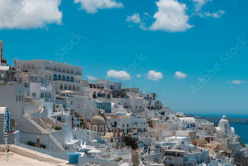 Santorini, Greece. Picturesque view of traditional cycladic Santorini houses on small street with flowers in foreground. Location: Oia village, Santorini, Greece. Vacations background. © andreiko