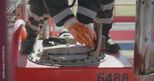 Closeup of engineer in uniform and gloves trying to open oil tank. photo