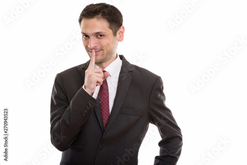 Studio shot of happy young businessman smiling with finger on li