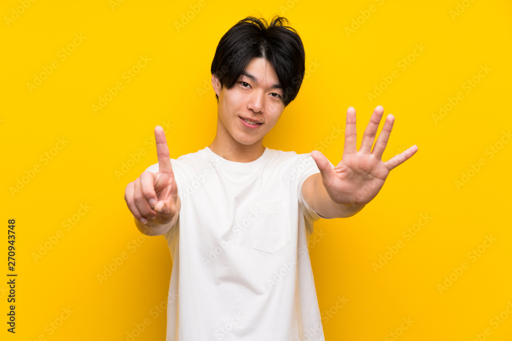 Asian man over isolated yellow wall counting six with fingers