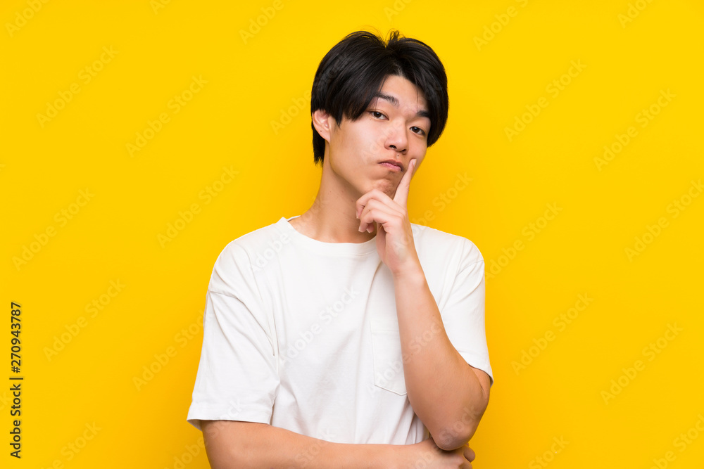 Asian man over isolated yellow wall Looking front