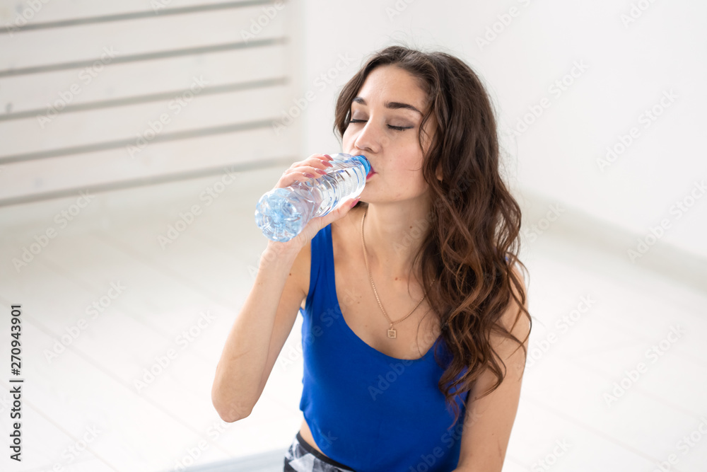 Healthy lifestyle, people and sport concept - Woman drinking water after workout Healthy lifestyle, people and sport concept - Woman drinking water after workout