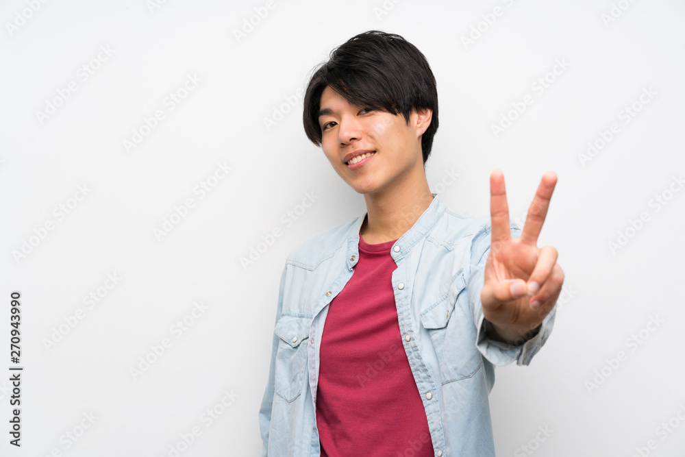 Asian man on isolated white background smiling and showing victory sign Asian man on isolated white background smiling and showing victory sign