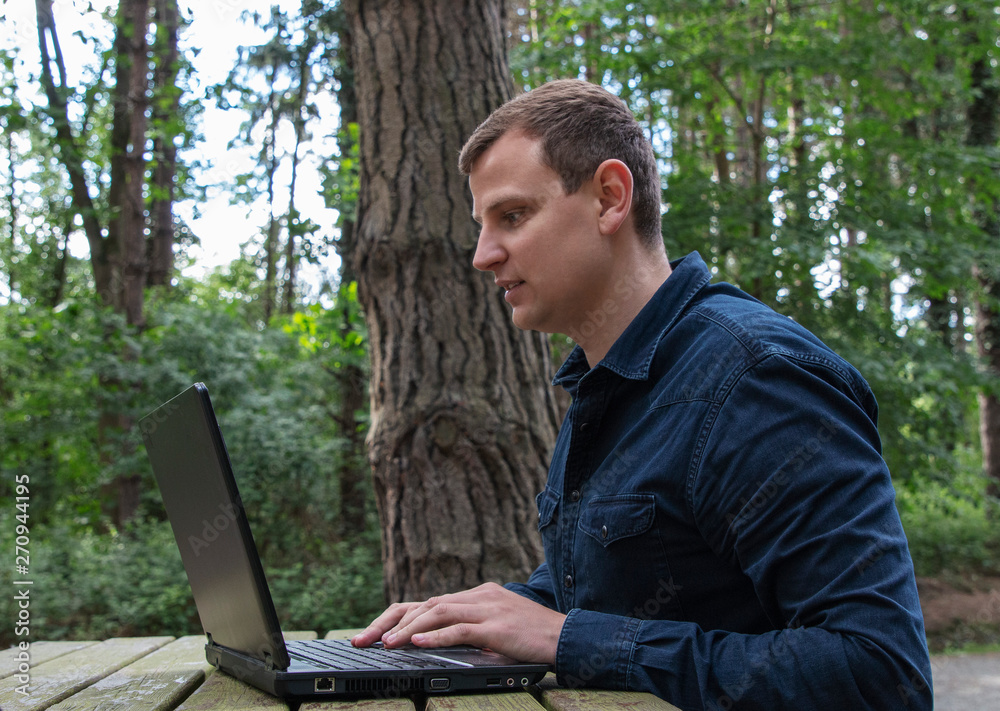 man work on computer in the fresh air in forest man work on computer in the fresh air in forest