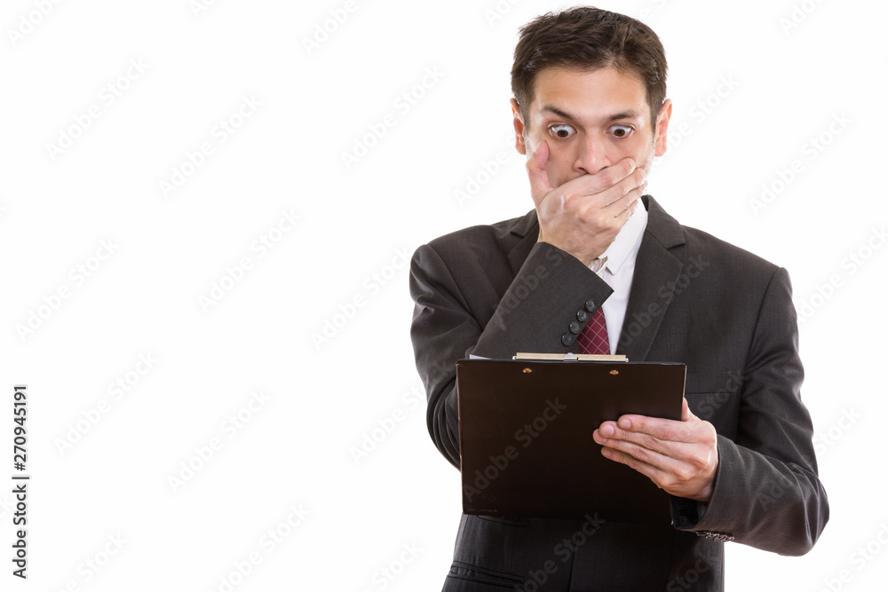 Studio shot of young businessman reading on clipboard while look Studio shot of young businessman reading on clipboard while look