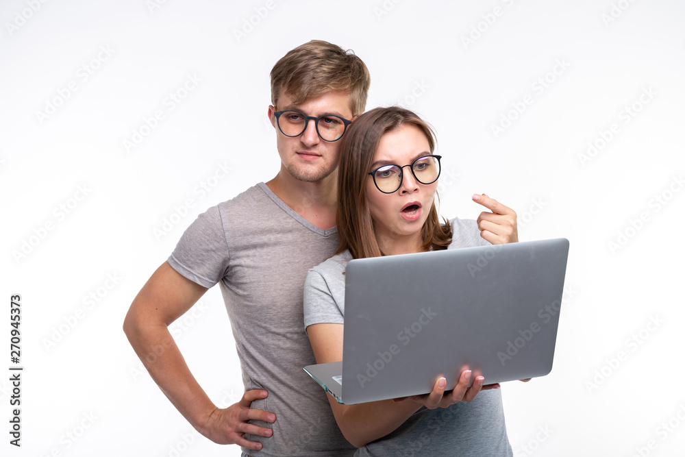 Nerds, study, people concept - a couple of students look at the netbook and look like scared on white background