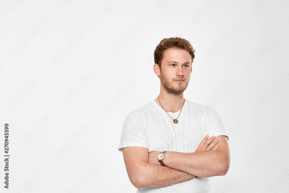 Confident handsome young man looks away the camera and keeps arms crossed Confident handsome young man looks away the camera and keeps arms crossed