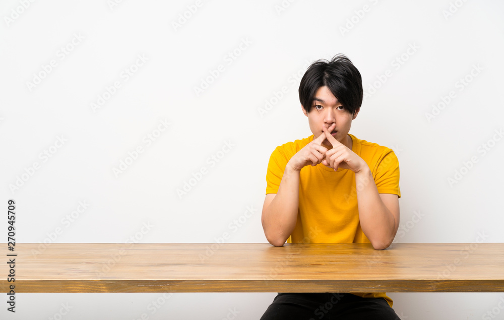 Asian man with yellow shirt showing a sign of silence gesture Asian man with yellow shirt showing a sign of silence gesture