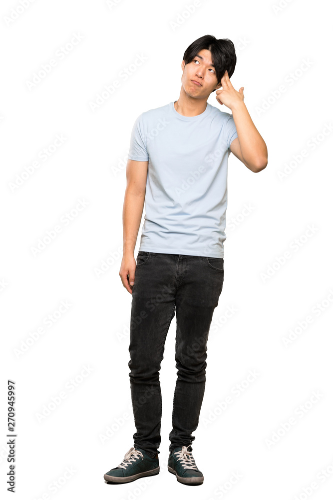 A full-length shot of a Asian man with blue shirt with problems making suicide gesture over isolated white background A full-length shot of a Asian man with blue shirt with problems making suicide gesture over isolated white background
