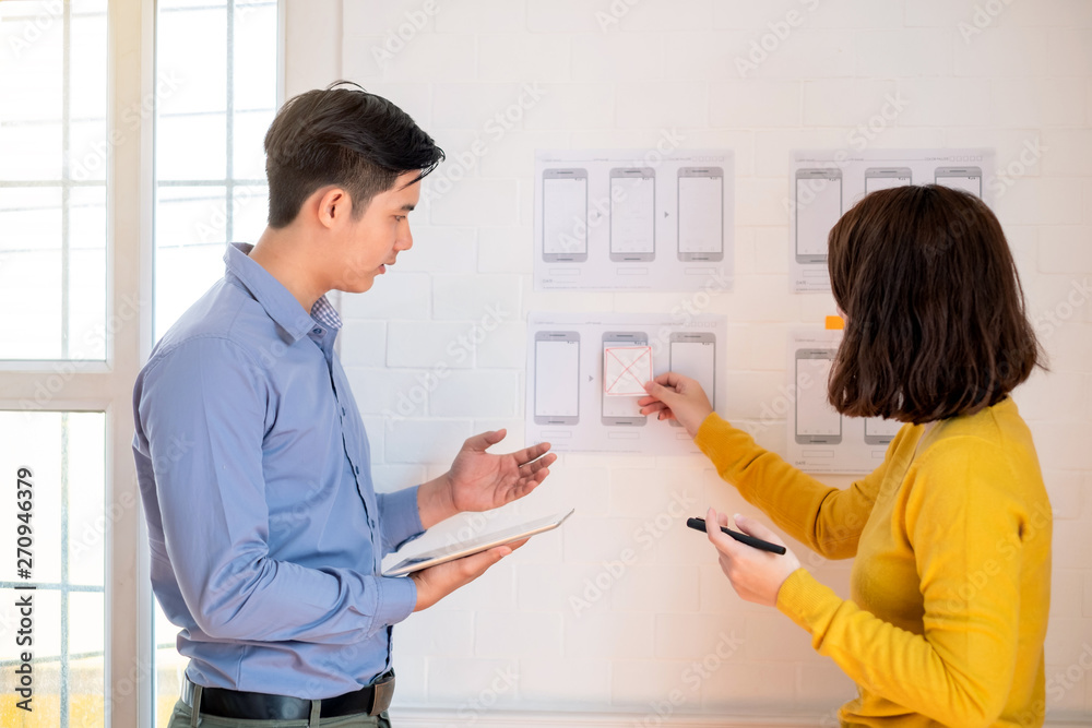 Two designers drawing a website outline and website ux app development on mobile phone. Two designers drawing a website outline and website ux app development on mobile phone.
