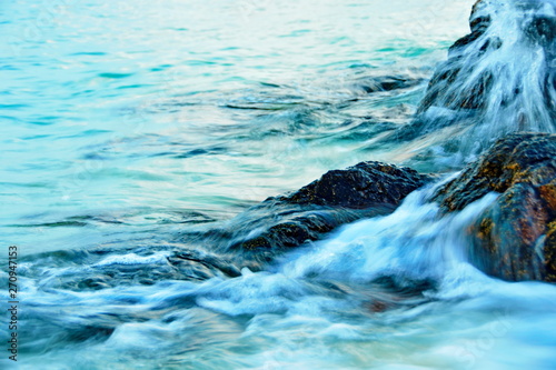 The background of the white sea waves strikes the rocky shore of the beach.