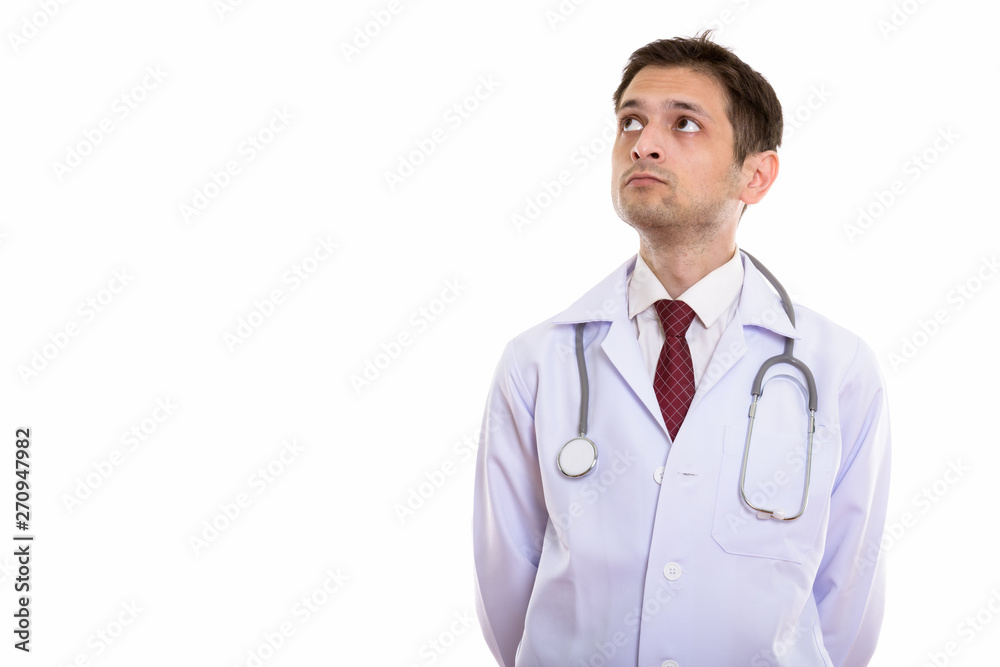 Studio shot of young man doctor thinking while looking up Studio shot of young man doctor thinking while looking up