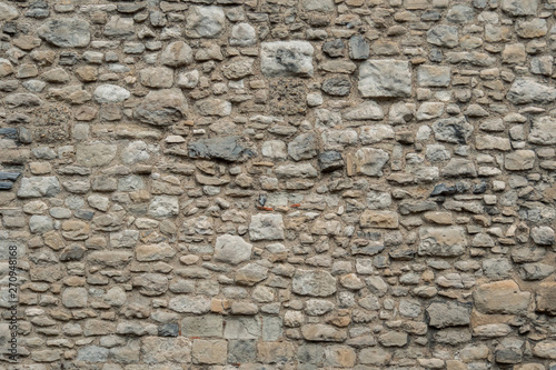 Pattern gray color of old style design decorative uneven cracked real stone wall surface with cement. Old beige stone wall background texture. Part of a stone wall, for background or texture.
