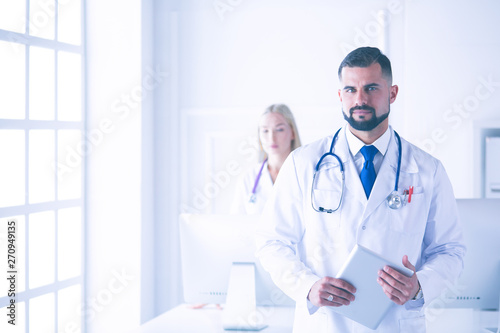 Wallpaper Mural Confident smiling doctor posing and looking at camera with arms crossed, medical staff working on the background Torontodigital.ca