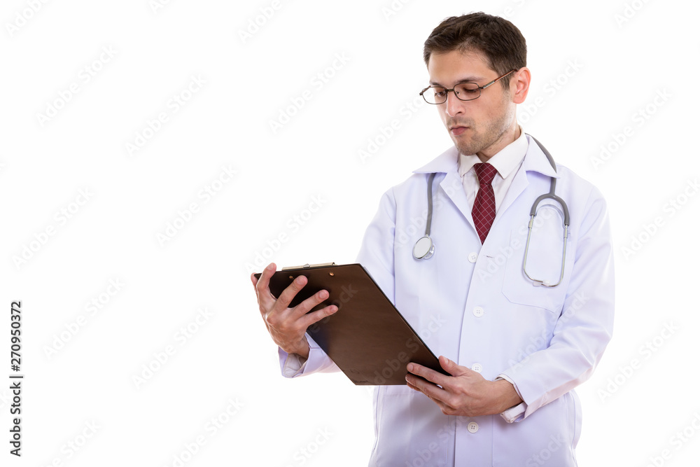 Studio shot of young man doctor reading on clipboard Studio shot of young man doctor reading on clipboard