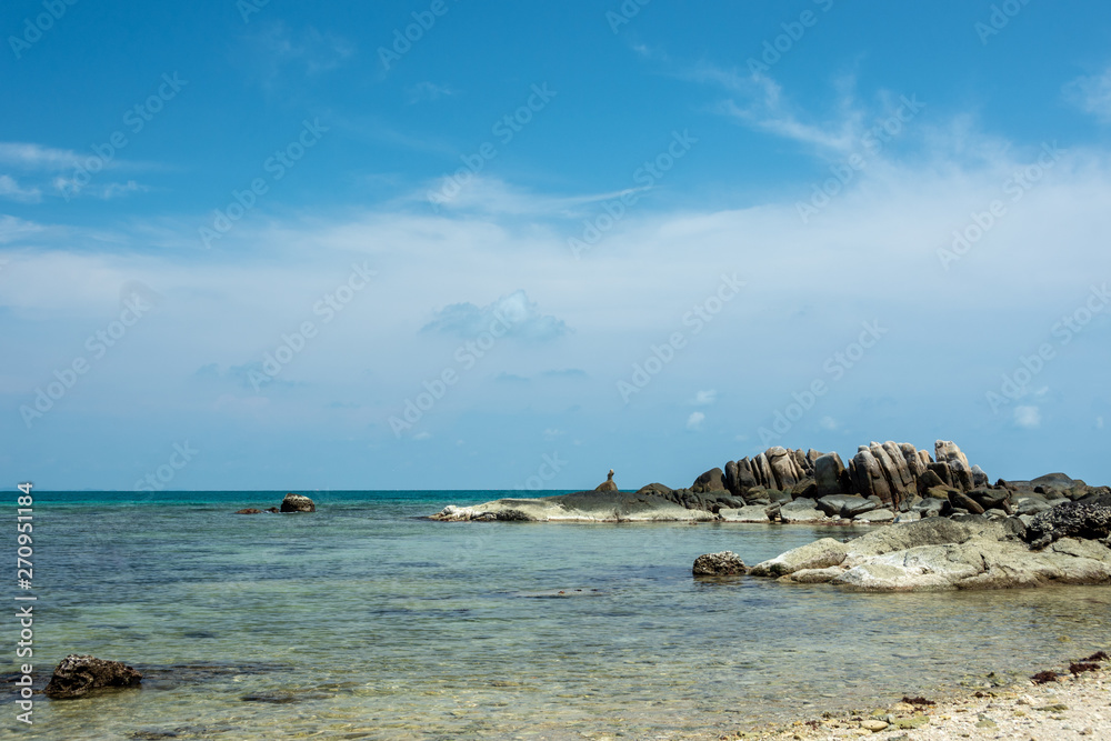 The background of a large rocky island in the blue sea and a blue sky