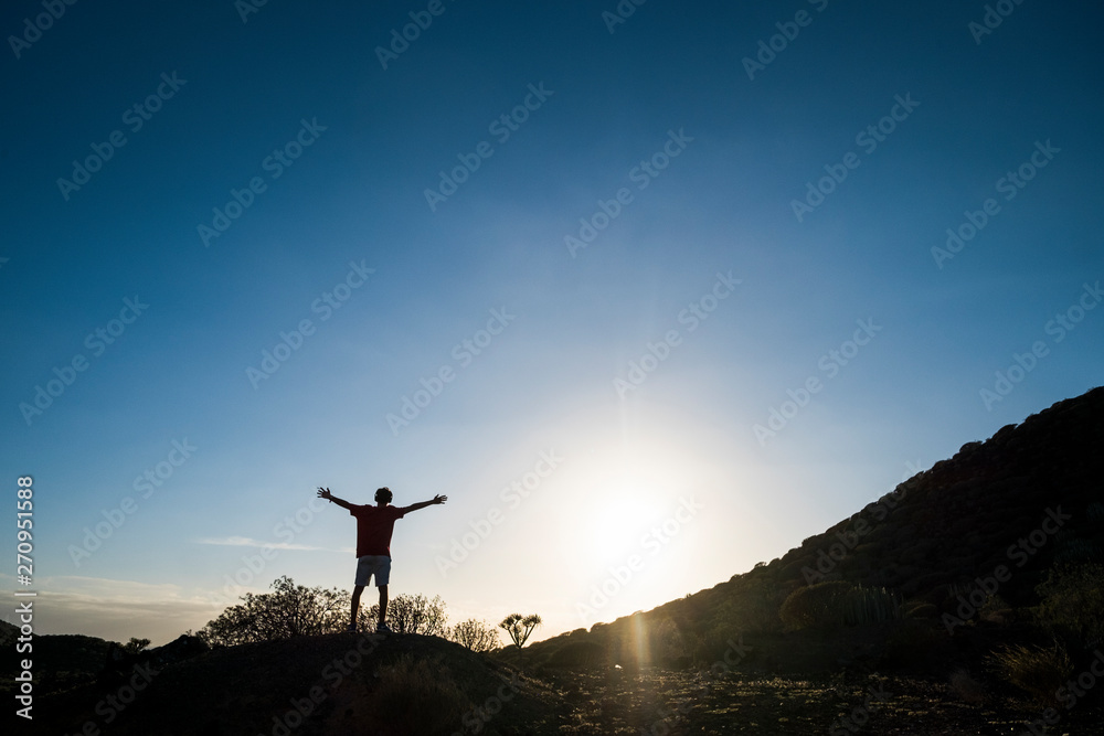 freedom concept lifestyle - man with arms open at the mountains with sunset - positive vibes