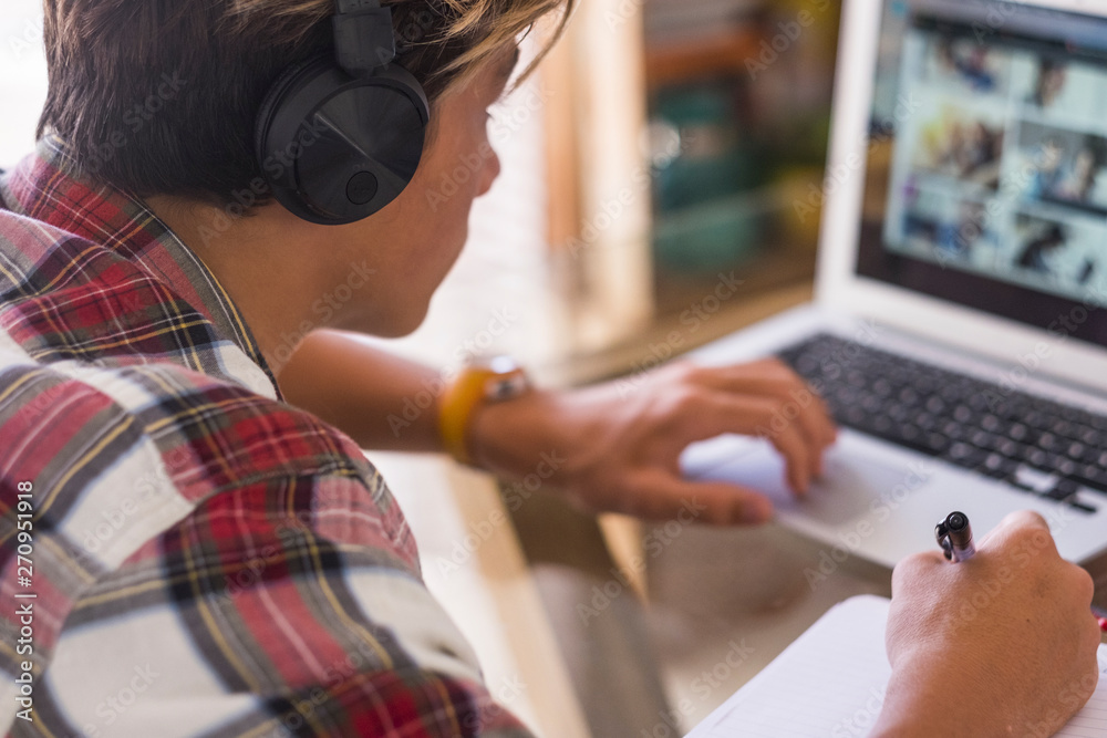 alone caucasian teenager focus for his homeworks with his laptop - millennial guy work at home - indoor kid playing videogames